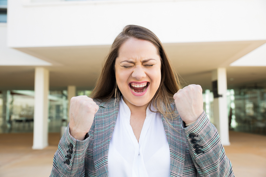 Cheerful business lady pumping fists outdoors